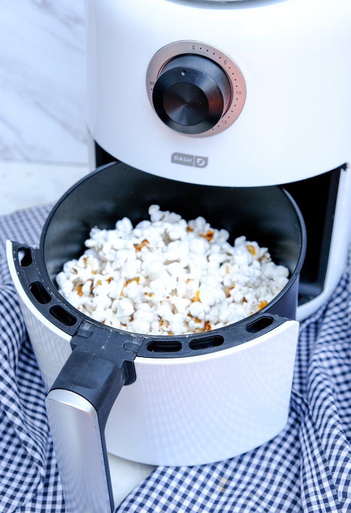 Popped popcorn in the basket of an air fryer.