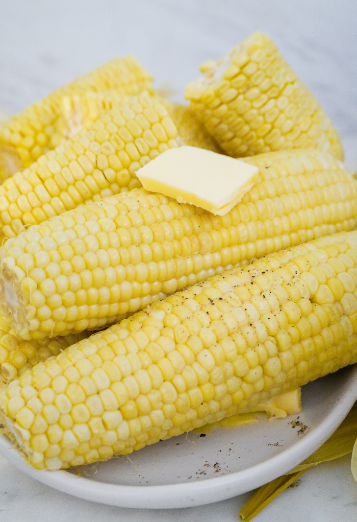 Cooked corn on the cob on a white serving platter.