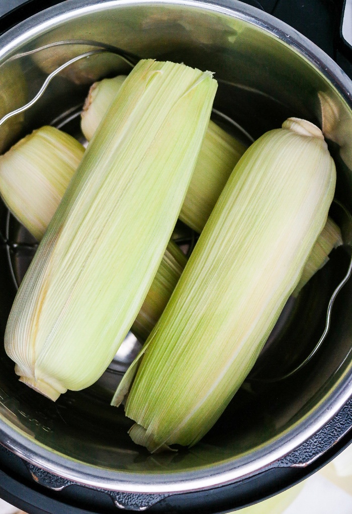 Corn on the cob in the husk in an Instant Pot ready to cook.