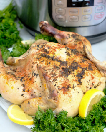 Whole chicken on a serving plate cooked in an Instant Pot.