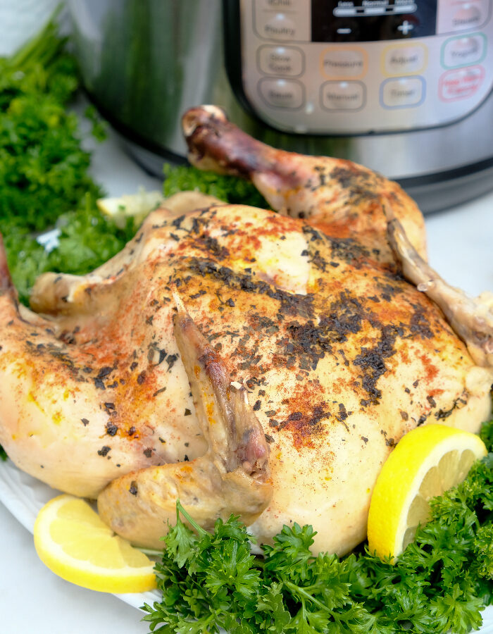 Whole chicken on a serving plate cooked in an Instant Pot.