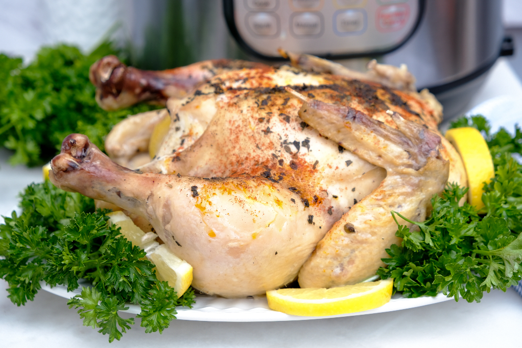 Whole chicken with lemon on a serving plate.  