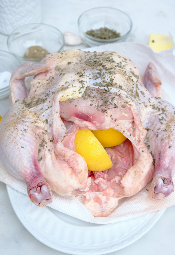 Raw chicken on a plate with seasoning ready to cook.