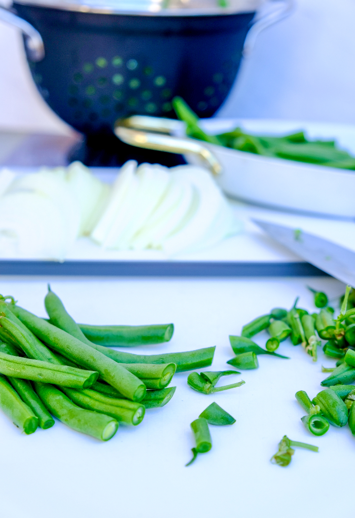 Slicing green beans on a cutting board.