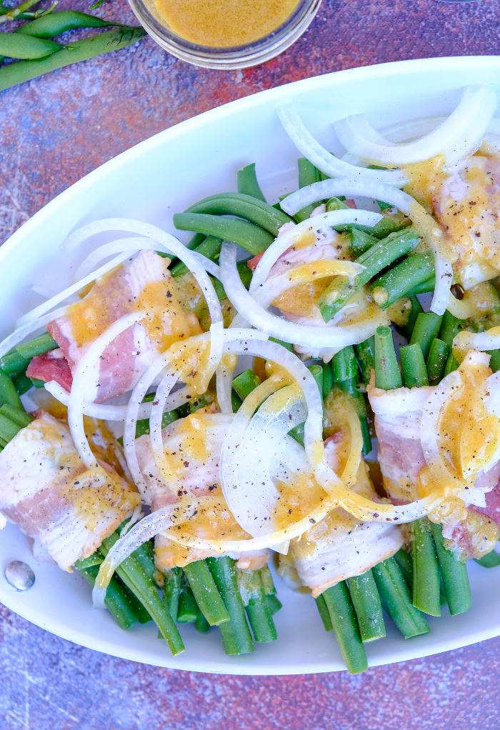 Bacon wrapped green beans with onion and seasoning ready to roast. 