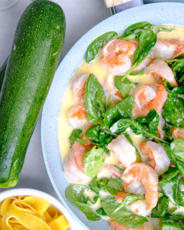 A skillet with cooked shrimp and spinach.