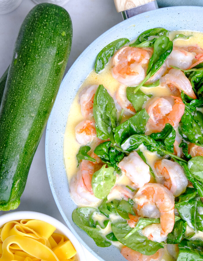 A skillet with cooked shrimp and spinach.