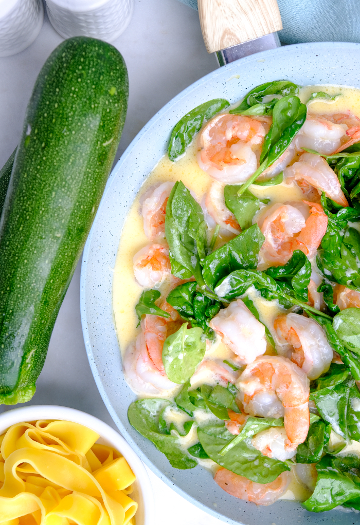 A skillet with cooked shrimp and spinach.