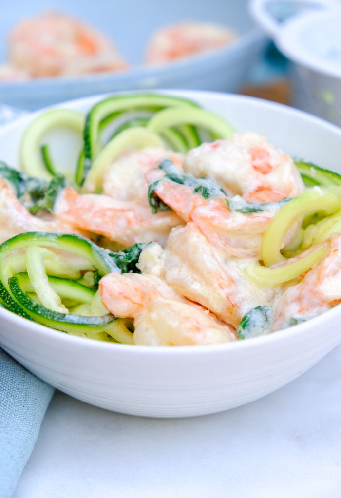 A small white bowl with shrimp and zucchini noodles. 