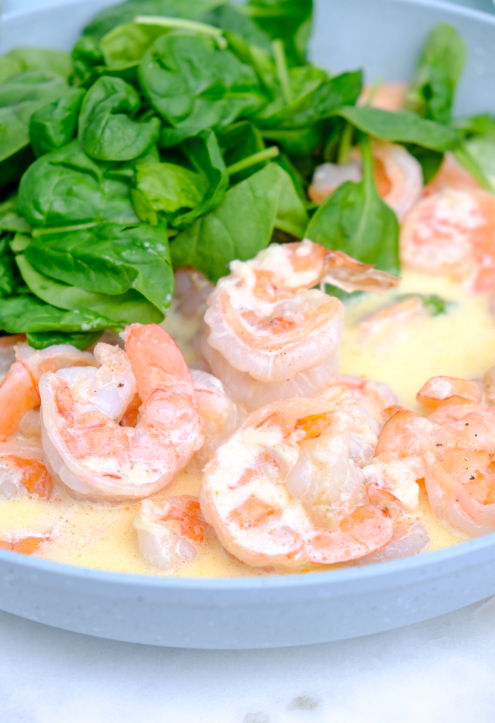 Cooked shrimp in a cream sauce with fresh spinach.