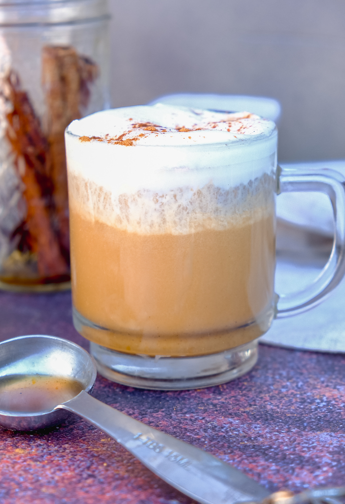 Pumpkin spice latte with whipped cream in a clear mug.