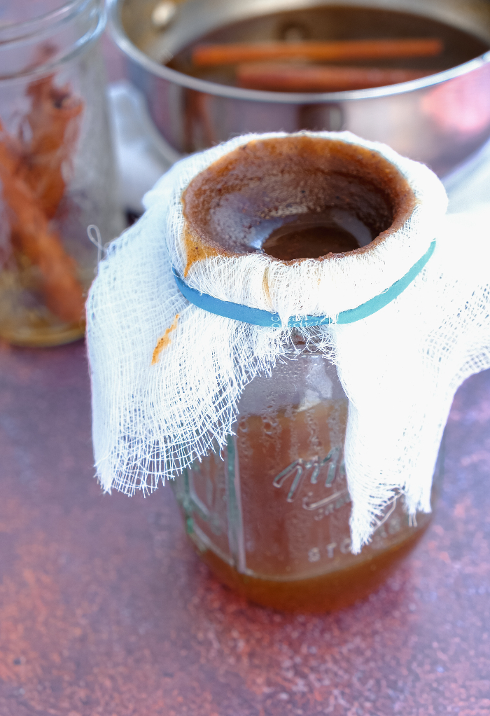 A Mason jar with cheesecloth with pumpkin spice syrup.