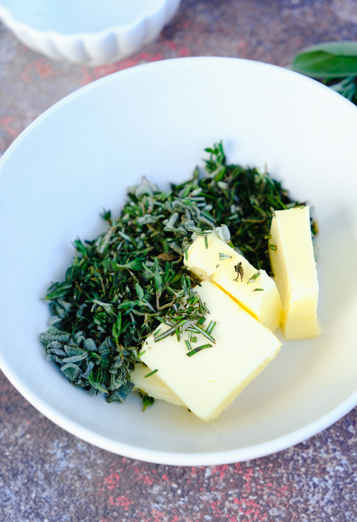 Butter and fresh herbs in a small white mixing bowl.