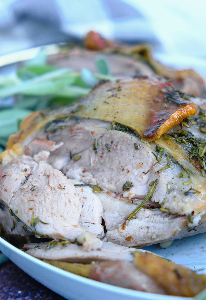 Cooked sliced roasted turkey thigh on a serving plate ready to eat. 