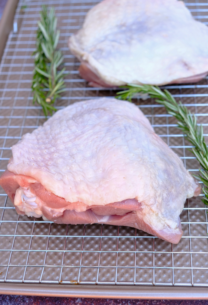 Salted turkey thigh resting on a baking sheet.