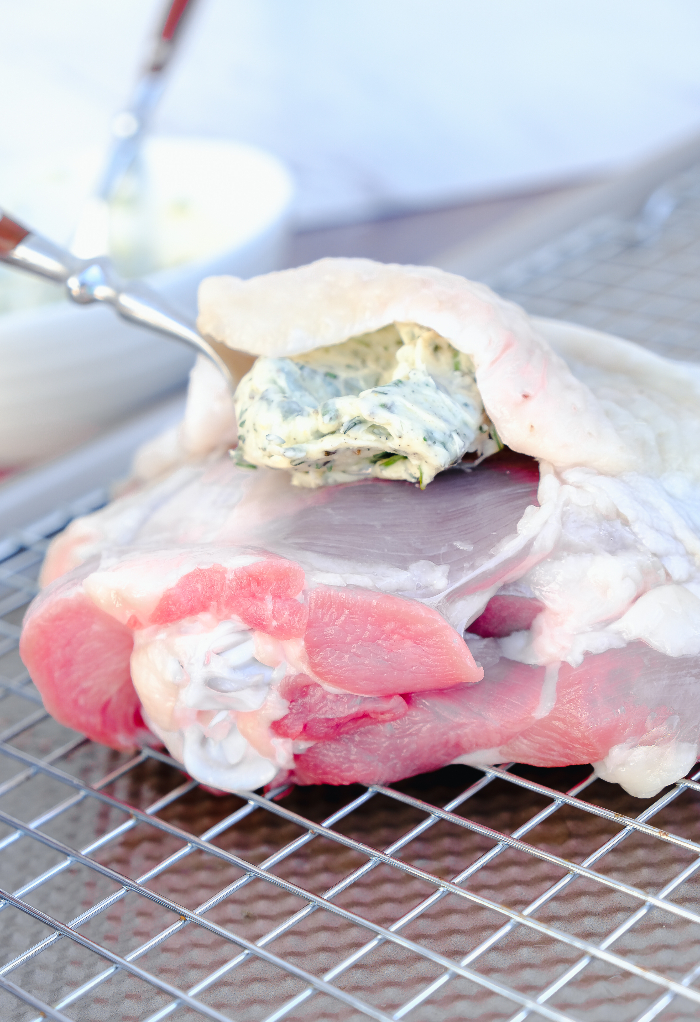 Preparing baked turkey thighs by placing herb butter mix on the turkey.