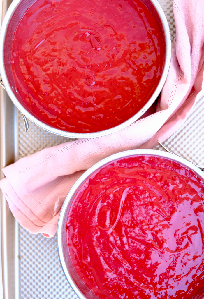 Homemade red velvet cake batter in springform pans ready to bake.