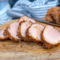 Air fryer pork tenderloin on a brown cutting board.