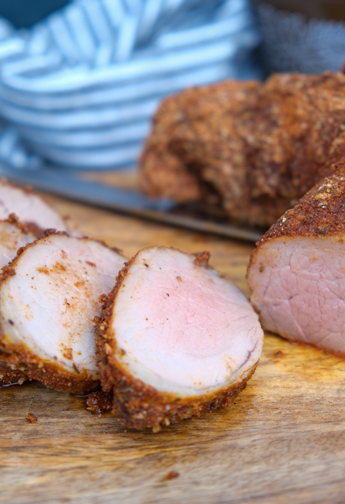 Pork tenderloin made in an air fryer sliced on a cutting board. 