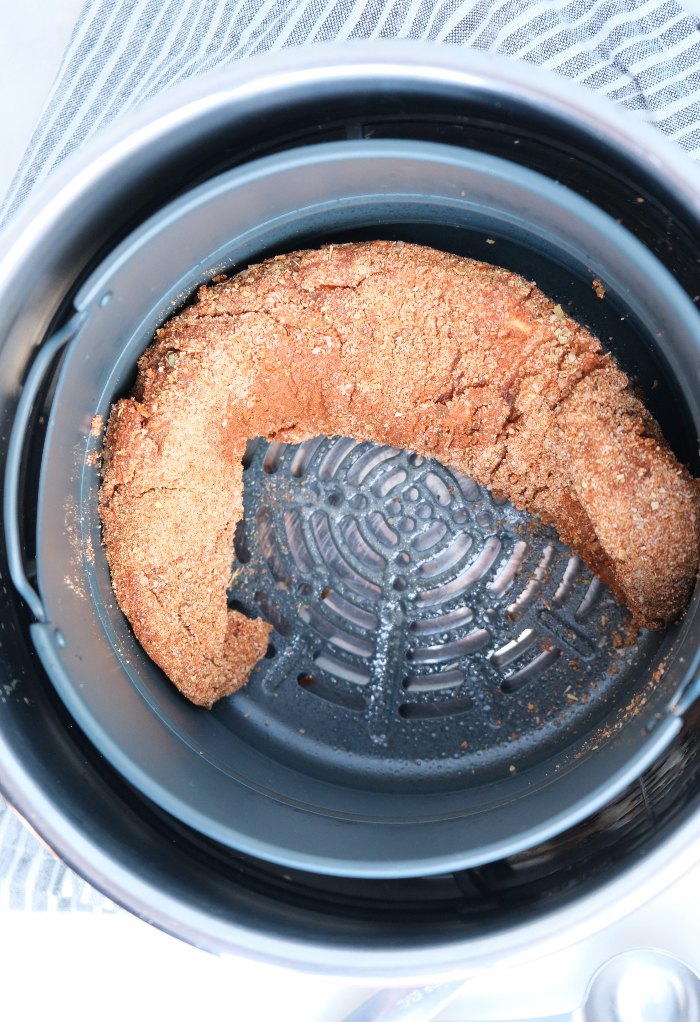 Center of an air fryer basket with an uncooked pork tenderloin.