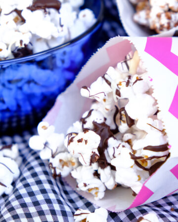 Popcorn drizzled in chocolate in small colorful paper bags ready to eat.