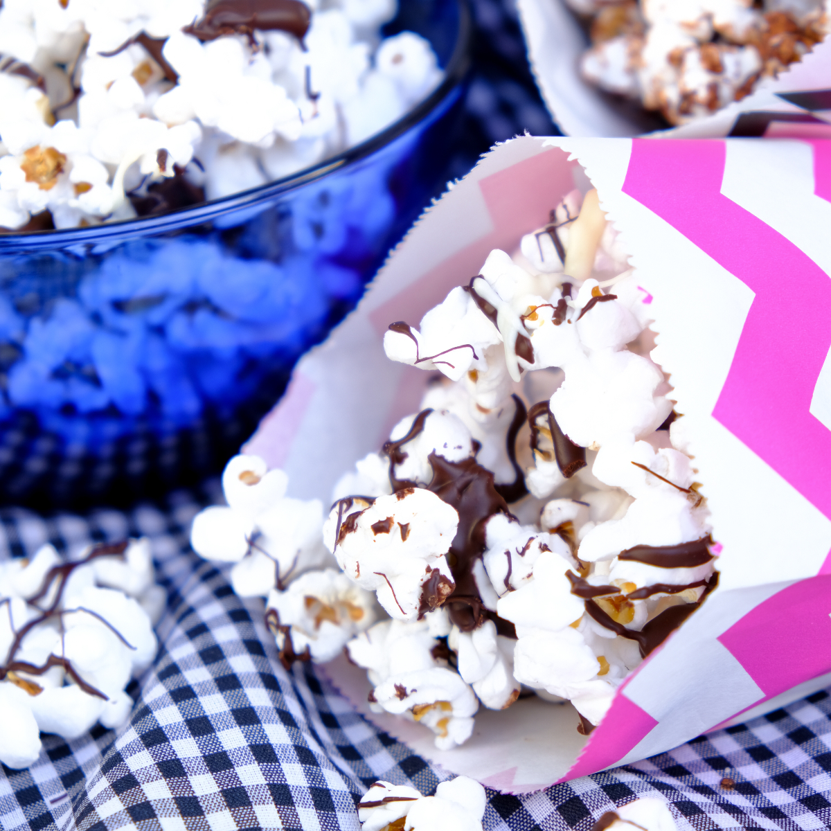 Popcorn drizzled in chocolate in small colorful paper bags ready to eat.