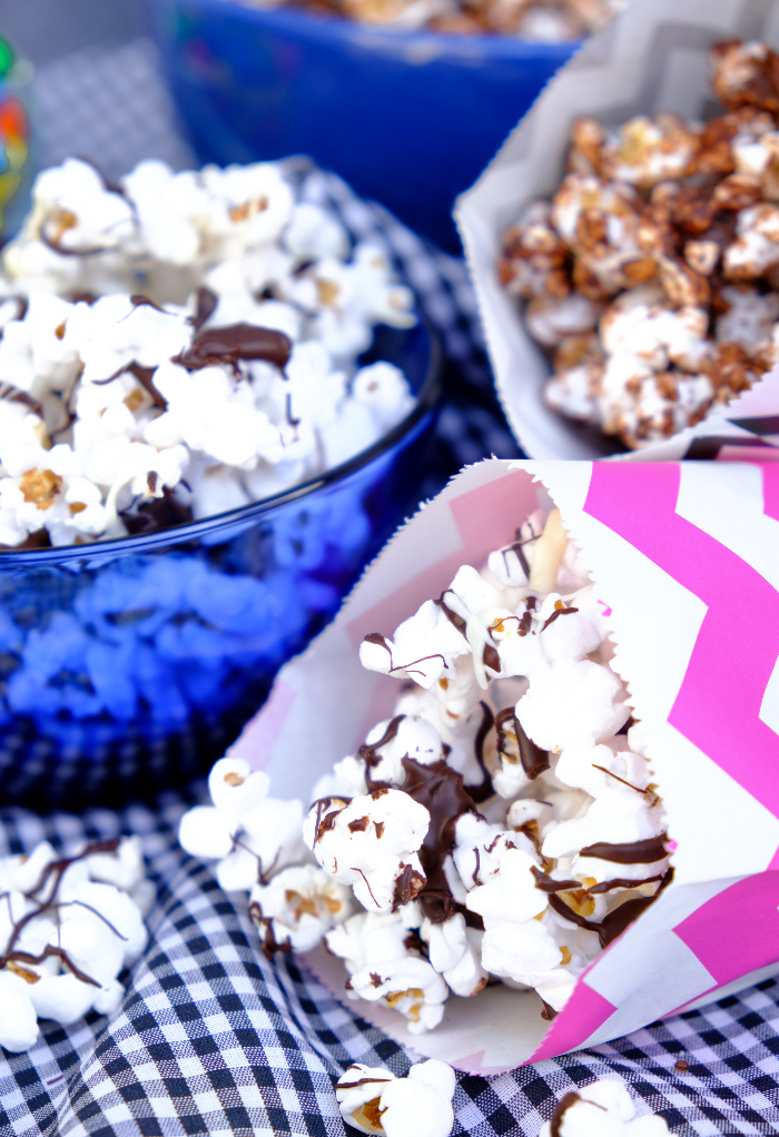 Chocolate drizzled popcorn in colorful bags and blue bowl.
