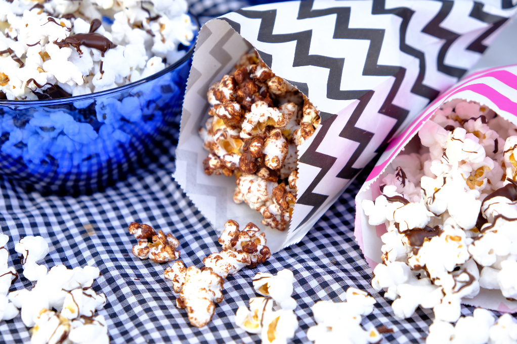 Popcorn in small colorful bags covered in melted chocolate. 