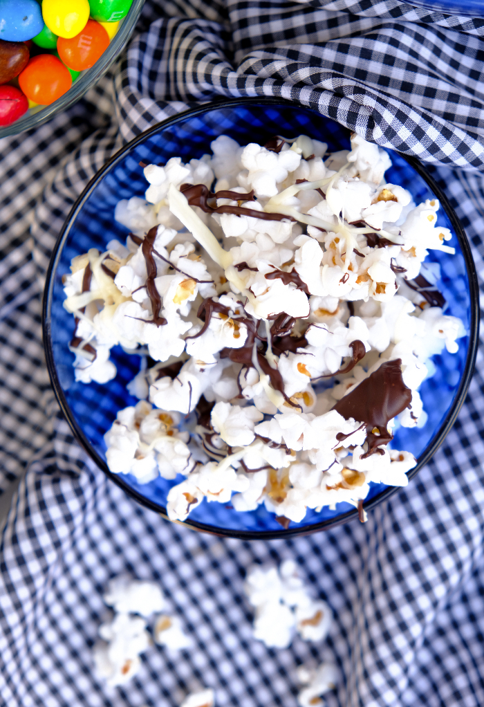 Top view of chocolate drizzled popcorn in a blue bowl ready to eat.