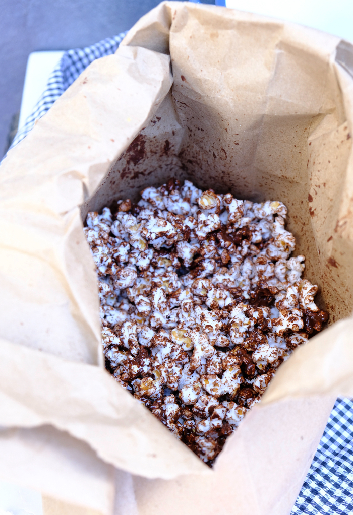 Popcorn covered in melted chocolate in a brown paper bag.