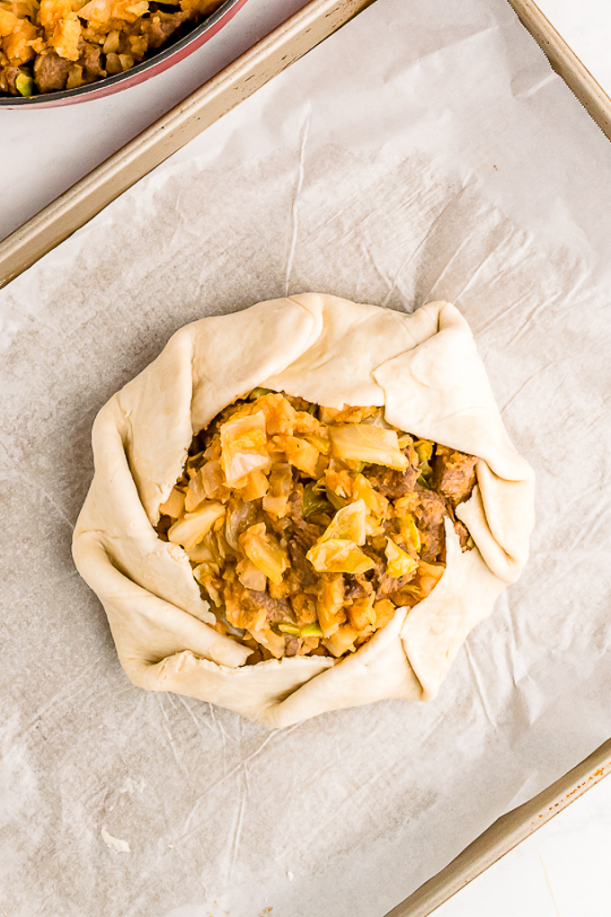 Pastry folded over meat and potato galette ready to bake.