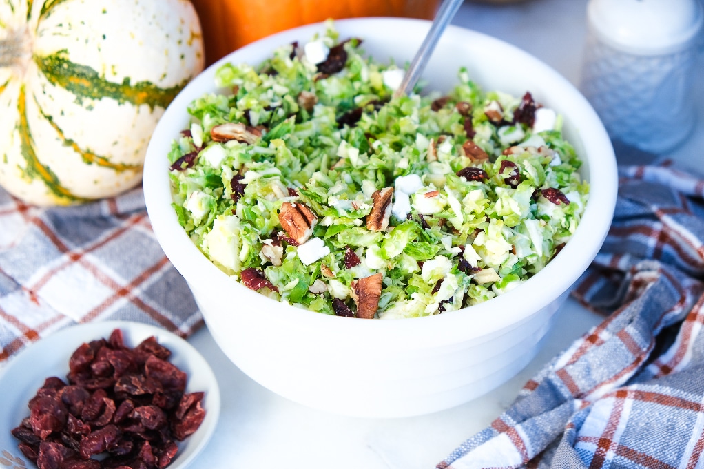 Brussel sprout salad with cranberries in a white serving bowl. 