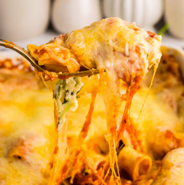 Spinach manicotti in a casserole dish being scooped up.