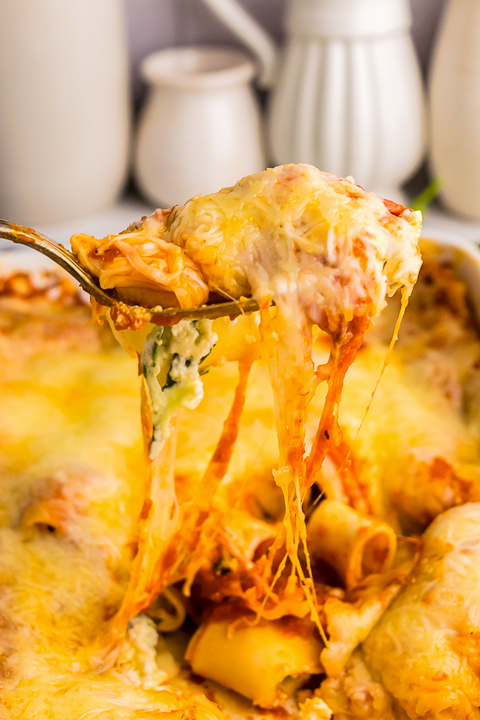 Spinach manicotti in a casserole dish being scooped up.