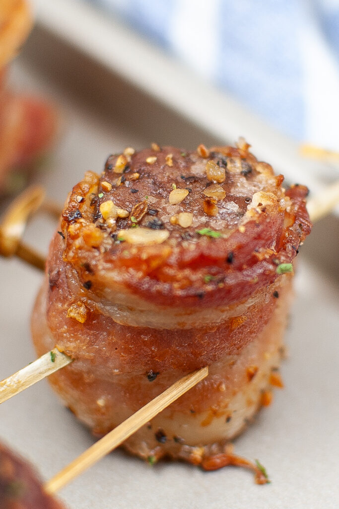 Steak bite wrapped in bacon on a baking sheet.