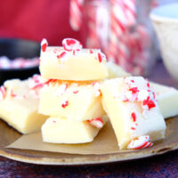 A small brown plate with white chocolate peppermint fudge squares topped with crushed candy canes.