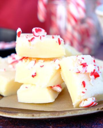 A small brown plate with white chocolate peppermint fudge squares topped with crushed candy canes.
