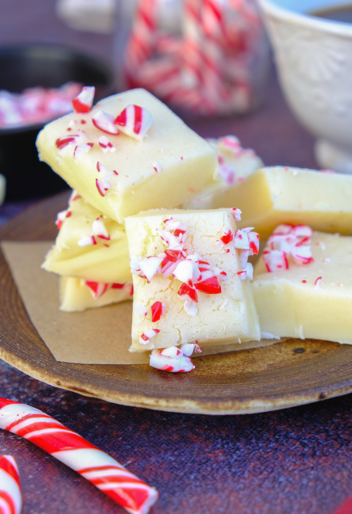 White chocolate fudge on a brown plate topped with crushed candy canes.