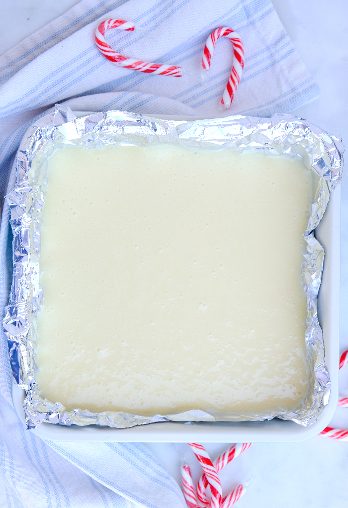 White chocolate peppermint fudge setting in a small aluminum lined baking pan.