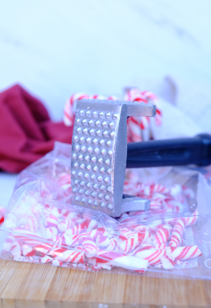 Crushing candy canes in a plastic bag with a mallet. 