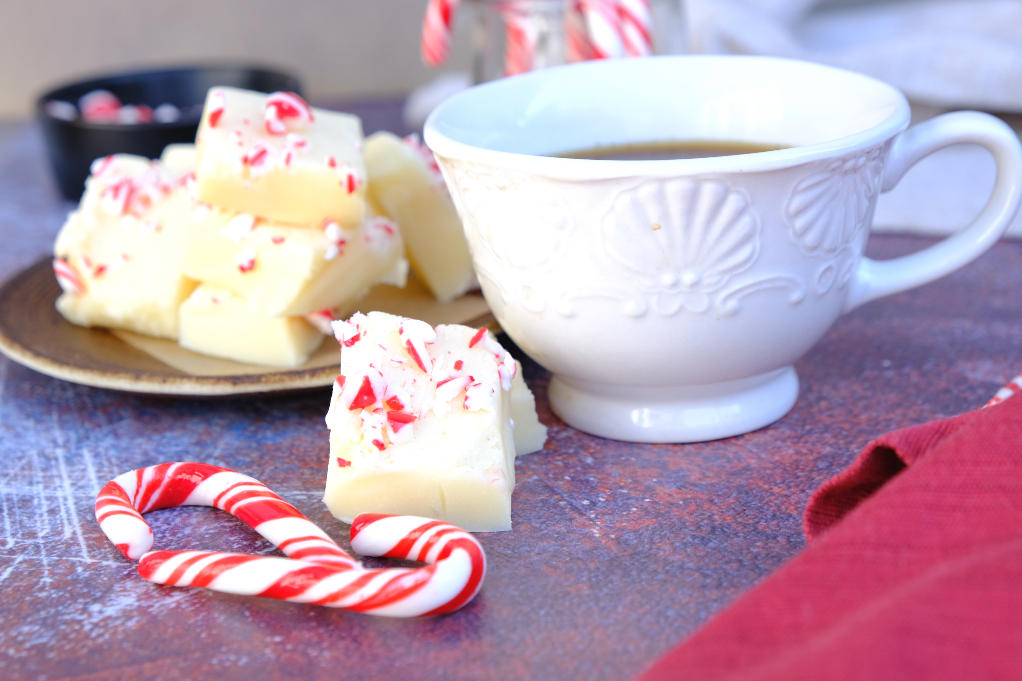 White chocolate peppermint fudge with a cup of tea in a white cup.