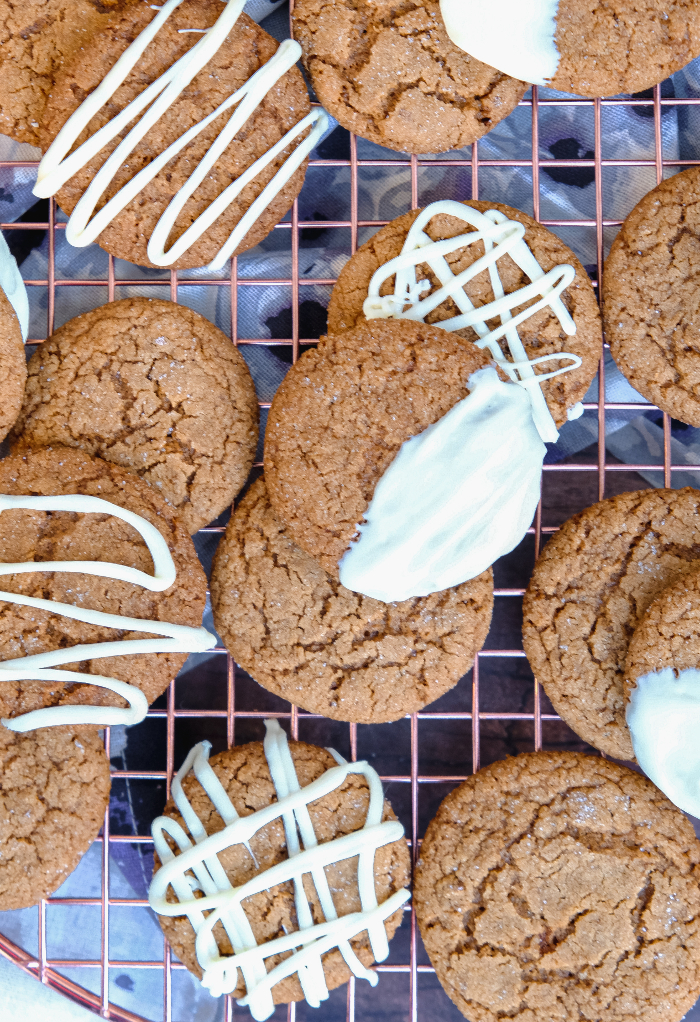 Crispy gingersnap cookies dipped in white chocolate on a cooling rack. 