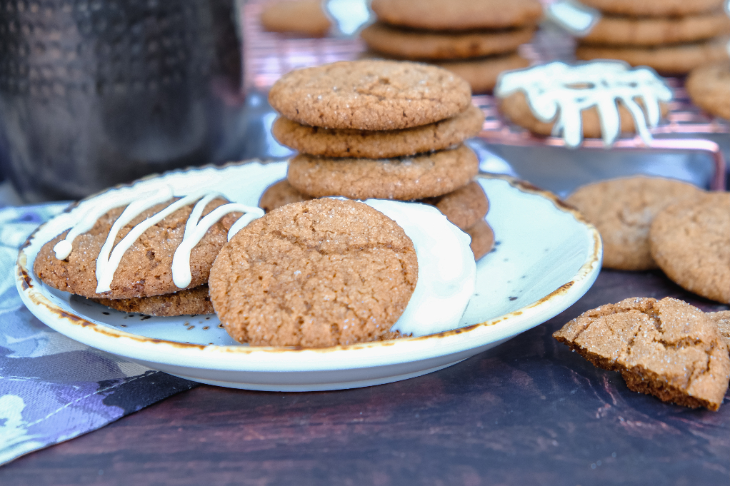 Crispy gingersnap cookies on a white plate with some cookies dipped in white chocolate ready to enjoy. 