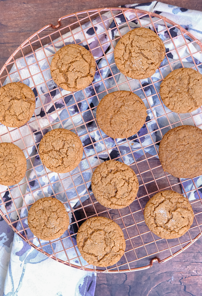 Baked gingersnap cookies cooling on a baking rack. 