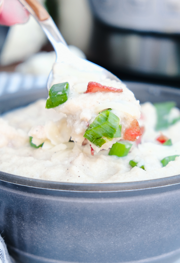 Spoonful of keto cauliflower soup scooping from a gray bowl. 