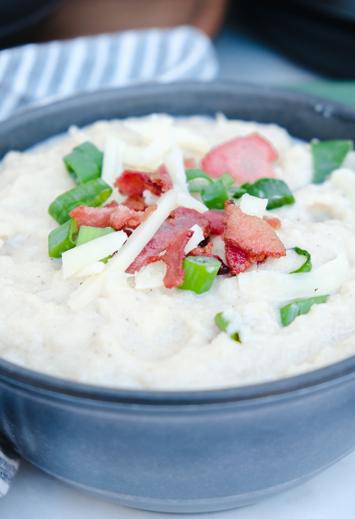 Keto cauliflower soup in a gray bowl with bacon and green onions ready to eat. 