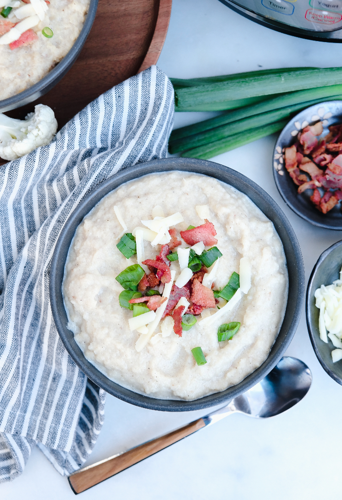 Top view of a gray bowl with cauliflower soup topped with bacon ready to enjoy.