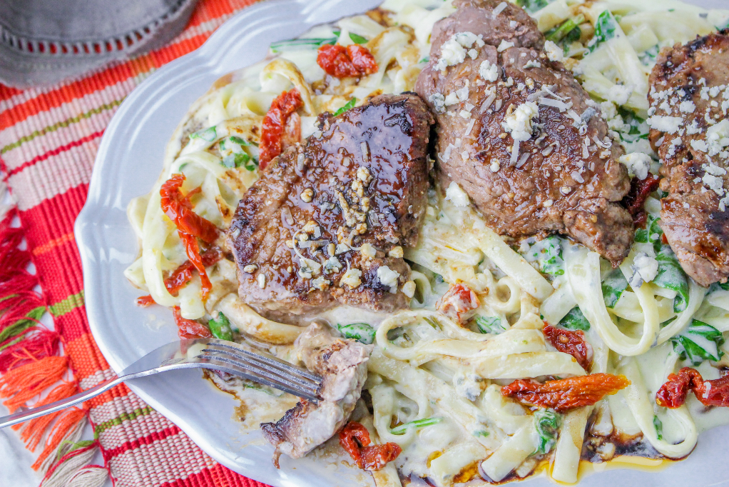 Copycat Olive Garden steak gorgonzola over pasta alfredo on a large white serving platter ready to enjoy.