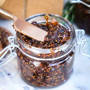 Homemade chutney in a clear jar with a knife for spreading.