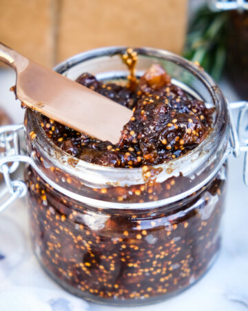 Homemade chutney in a clear jar with a knife for spreading.